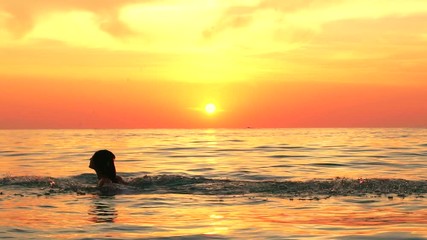 Woman splashes water with her hair at beautiful summer sunset. Slow motion