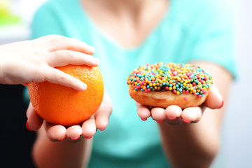 Educate children to choose healthy food concept with little girl choice to eat fruit, not a donut  
