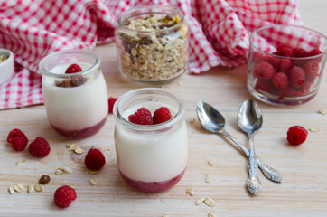 Fruit on the bottom yogurt jars and muesli on wooden background. Yoghurt with raspberry jam. Concept for heathy eating or breakfast.