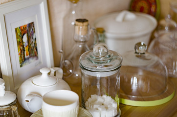 Simple rustic kitchenware against white wooden wall: rough ceramic pot with wooden cooking utensil set, stacks of ceramic bowls, jug and wooden trays.