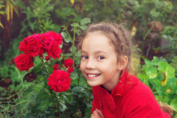 Portrait of Little Girl in the Summer time. Beautiful Girl smiling in rose Garden
