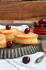 Whole and slice of cherry custard pie served on a vintage baking form on a wooden background.
