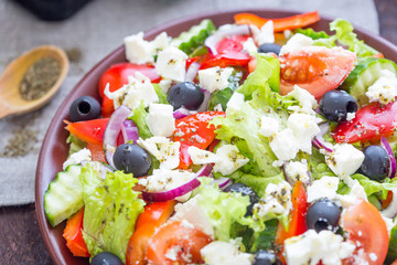 Greek Salad in the Plate on Dark Brown Wooden Table, Horizontal View