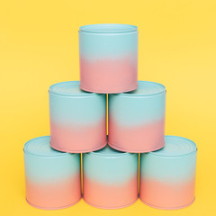 six painted jars with dip-dyed pink and blue colors stand like pyramid on yellow background