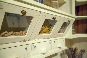 We can see hazelnuts and past in different drawes in a beautiful vintage cupboard. The kitchen has a unique style.