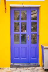 Fototapeta na wymiar Purple door with glass on the yellow wall