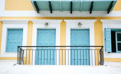 Fototapeta na wymiar Balcony on the yellow house with turquoise doors and windows