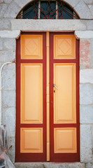 Red and yellow wooden door on a stone wall