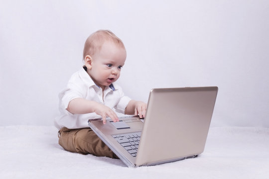 Concentrated baby boy playing or programming on laptop. Concept of new it generation
