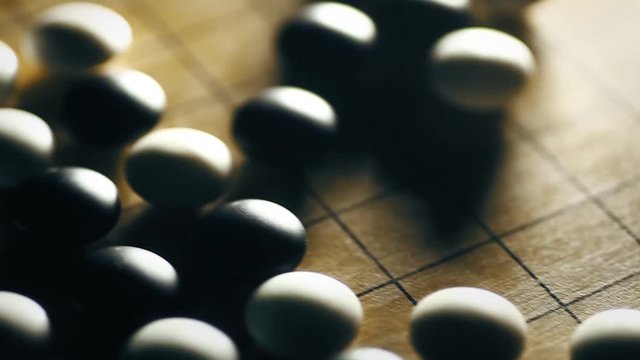 Horizontal dolly shot of a Go board game, with black and white stones.