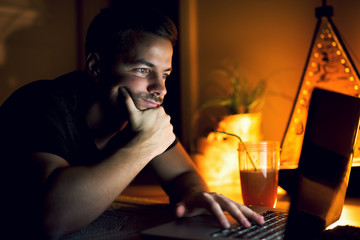 Nice man lying on floor drinking juice, surfing internet.
