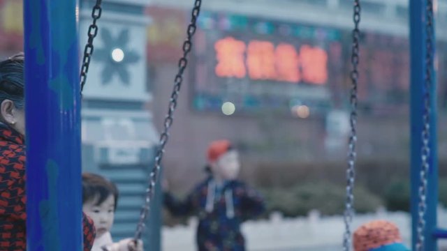 Chinese cute kids wearing masks ride on a swing
