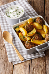 Delicious baked potato with meat balls and herbs in a dish close-up. vertical