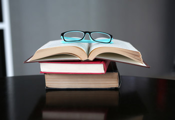 Open stack hardback books with glasses on wooden table. Education background.