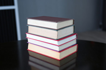 Stack of hardback books on wooden table. Education background.