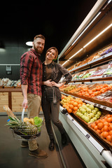 Happy young loving couple standing in supermarket