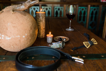 Men’s rings in bronze plate on a wooden table and burning candle. Men’s accessories. Wooden necktie.  Leather belt 