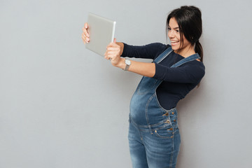 Happy pregnant woman make selfie by tablet computer