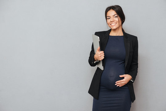 Happy pregnant business woman holding laptop computer