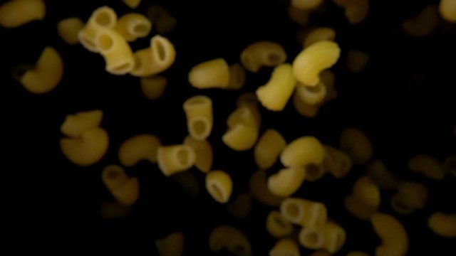 Pasta chifferi bouncing against to the camera on a black background in slow motion