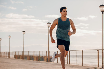 Fit young man running on seaside promenade
