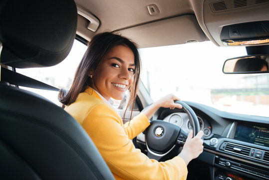 Back view of a confident smiling woman driving car
