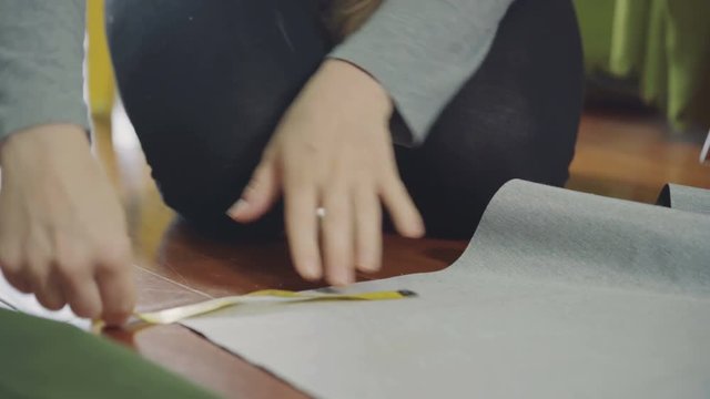 A woman measures and delineates the fabric