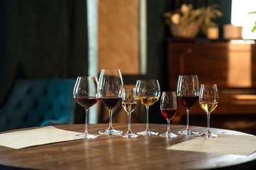 Collection of wine glasses with different wine on wooden table in restaurant. Life style