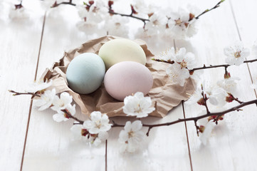 Fototapeta na wymiar Colored eggs with flowers on a white wooden background. The concept of the holiday of Easter.