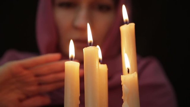 woman doing the magic ritual. close-up several candle. halloween or religion concept