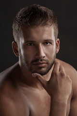 Model man with an open  chested on a dark background , muscular body of a young man in jeans . Shot in a studio .