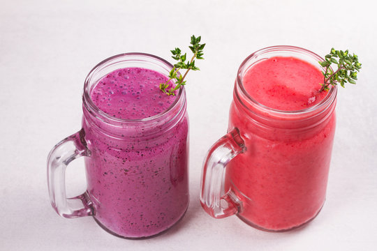 Summer berries smoothie in the jars on white rustic background