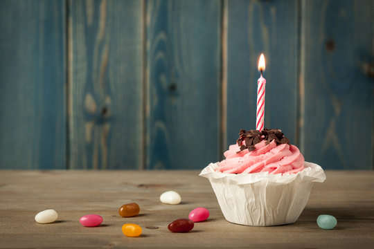 Homemade Birthday cupcake with candle and colorful candies