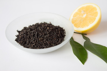 Dry tea in a beautiful bowl and lemon with green leaves