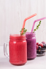 Summer berries smoothie in the jars on white rustic background