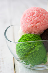 Ice cream scoops in crystal bowl on white wooden table
