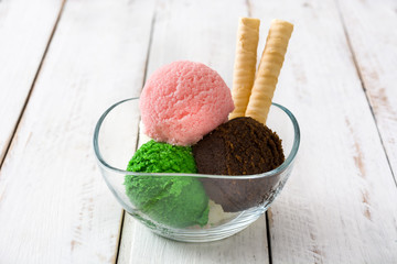 Ice cream scoops in crystal bowl on white wooden table
