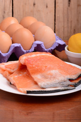fresh salmon fillet close up on white plate. eggs and lemon