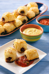 Homemade sausage rolls on wooden background.