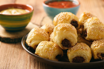 Homemade sausage rolls on wooden background.