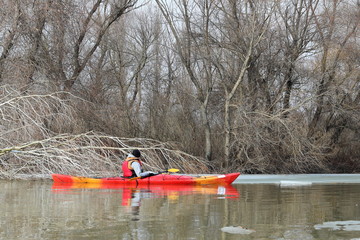 Guy in red kayak in winter Danube river. Winter kayaking