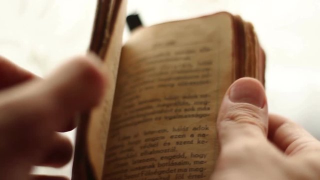 Prayer hands holding a vintage Bible.