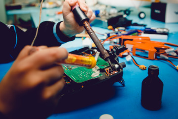 Airplane on the radio control. Repair, soldering iron in the hands of the guy. - obrazy, fototapety, plakaty