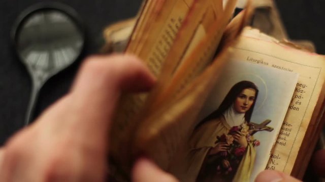 First the hand searching in a religious book then using magnifying glass too.