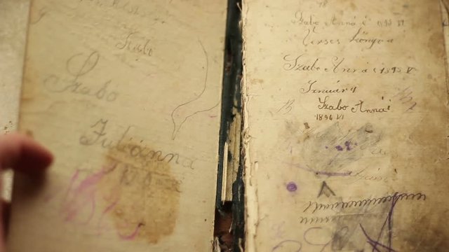 Hands searching in a vintage manuscript with magnifying glass. 