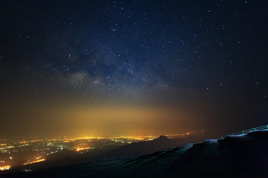 Milky way galaxy and city light at Phutabberk Phetchabun in Thailand.Long exposure photograph.With grain