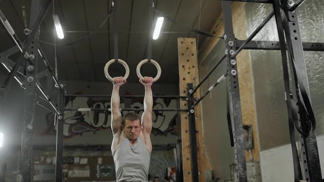 Male man athlete working out his muscles on rings, crossfit acrobat training