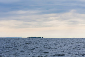 Victoria Lake with hazy island optical illusion (mirage) in horizon against overcast morning sky background. Entebbe, Uganda, Eastern Africa.

