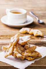 A pile of faworki and a cup of tea in the background