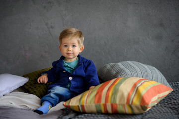 Fototapeta premium Little boy sits on a bed.